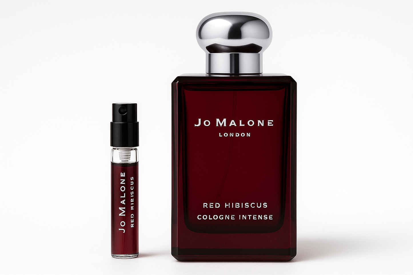 Mostră de 2ml Jo Malone Red Hibiscus Cologne Intense, așezată lângă sticla de parfum de 100ml Jo Malone Red Hibiscus Cologne Intense, care are scris alb pe sticla roșu închis.